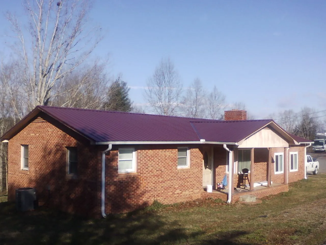 Burgundy metal roof on a brick ranch home with a new addition in Dennison