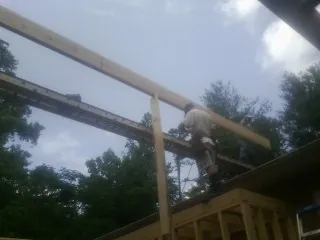 Carpenter setting a ridge beam over a new addition frame — Ice Dam Removal by Roofing Brothers in Dennison