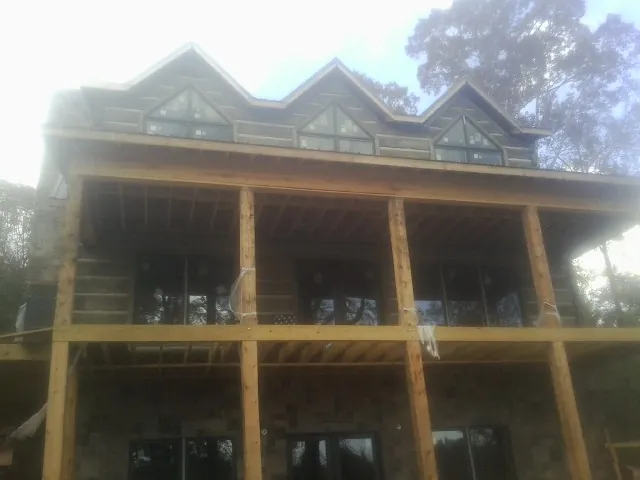 Dormers and porch framing on a large log home under construction — Roof Coating work by our crew in Dennison